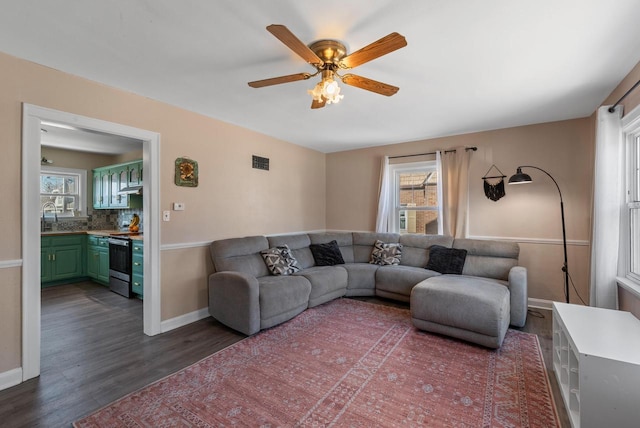 living area with ceiling fan, visible vents, baseboards, and dark wood finished floors