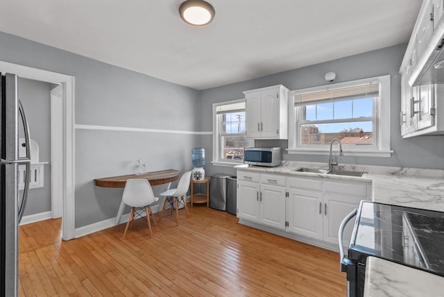 kitchen featuring white cabinetry, light wood-style flooring, appliances with stainless steel finishes, and a sink