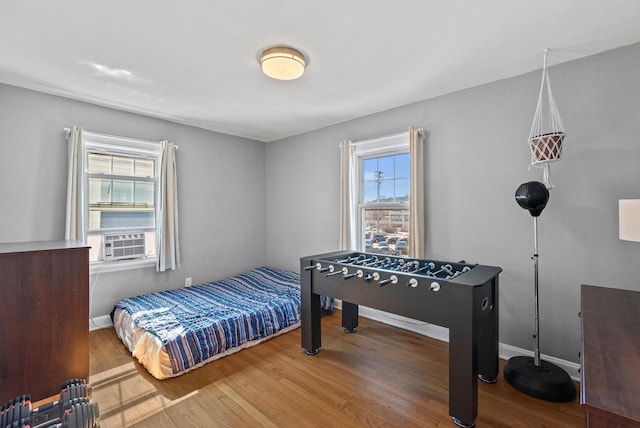 bedroom featuring cooling unit, baseboards, and wood finished floors