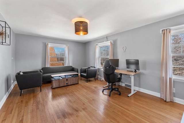 office area featuring a wealth of natural light, visible vents, baseboards, and light wood finished floors