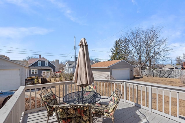 wooden terrace with an outbuilding, fence, outdoor dining area, a garage, and a residential view