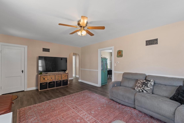 living room featuring arched walkways, visible vents, ceiling fan, and wood finished floors