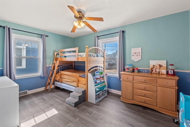 bedroom featuring ceiling fan, visible vents, baseboards, and wood finished floors