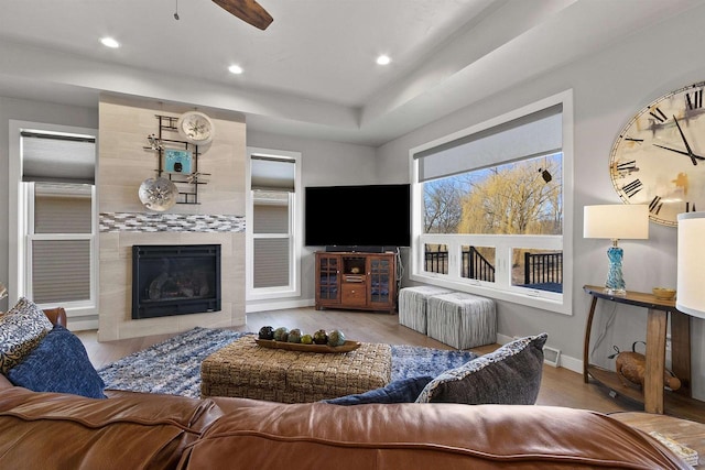 living room featuring recessed lighting, a premium fireplace, baseboards, and wood finished floors