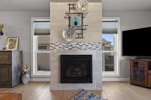 living room with baseboards, hardwood / wood-style floors, and a tiled fireplace