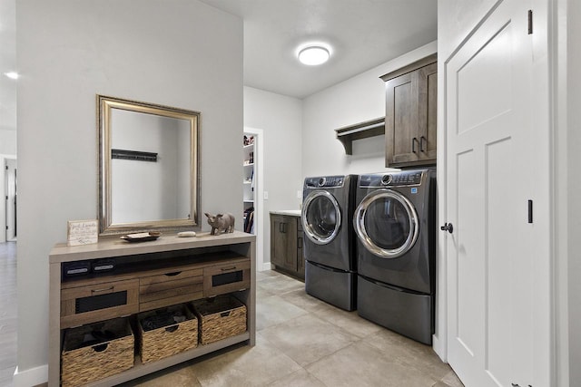 clothes washing area featuring light tile patterned floors, cabinet space, and washer and clothes dryer