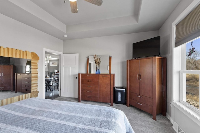 bedroom featuring light colored carpet, a raised ceiling, and a ceiling fan