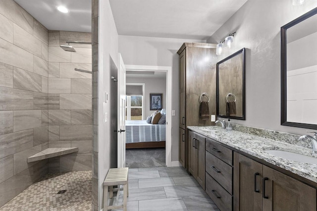 full bath featuring double vanity, tiled shower, ensuite bathroom, and a sink