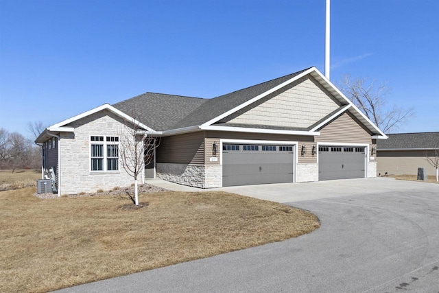 craftsman-style home with stone siding, cooling unit, roof with shingles, concrete driveway, and an attached garage