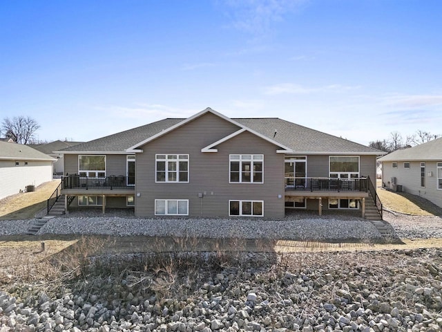 back of property with stairs, a deck, and a shingled roof