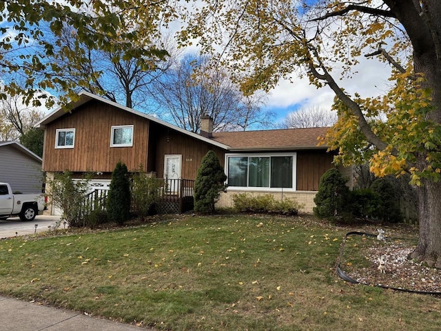 view of front of home with a front lawn, concrete driveway, brick siding, and a chimney