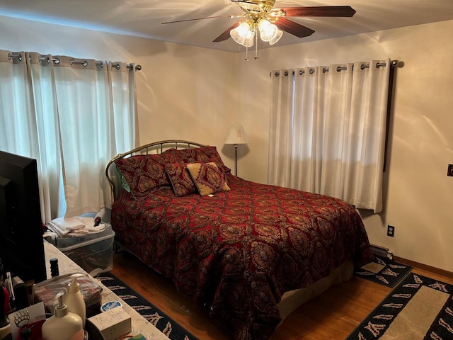 bedroom with a ceiling fan, wood finished floors, and baseboards