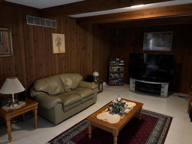 living room featuring beam ceiling, wooden walls, and visible vents