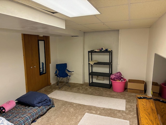 finished basement with a drop ceiling, concrete block wall, and carpet floors