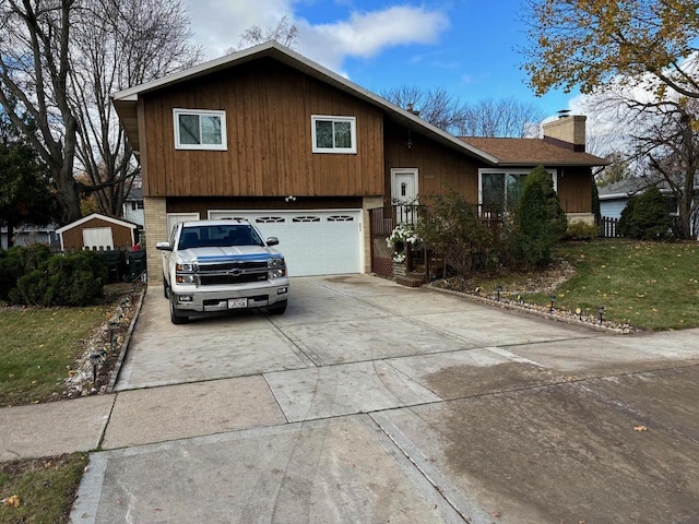 split level home featuring a garage, driveway, brick siding, and a chimney