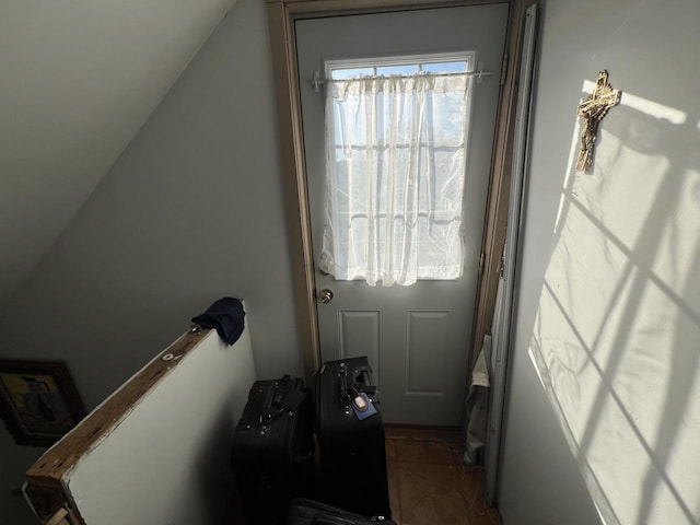 doorway with tile patterned floors and vaulted ceiling