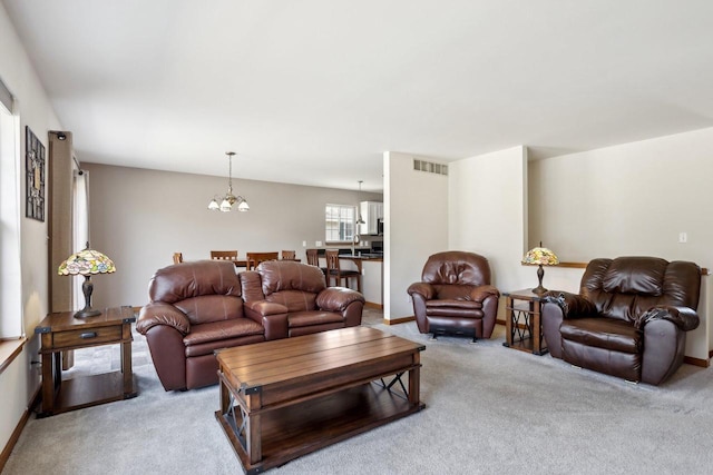 carpeted living area featuring a notable chandelier, baseboards, and visible vents