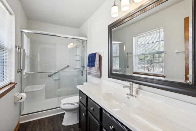 bathroom featuring toilet, a stall shower, vanity, and wood finished floors