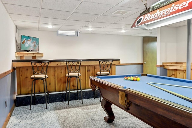 game room with carpet flooring, wainscoting, a dry bar, and a drop ceiling