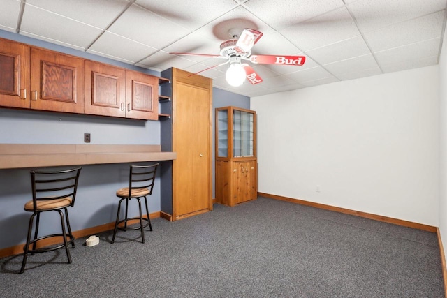 interior space featuring carpet, a breakfast bar, open shelves, a drop ceiling, and brown cabinets