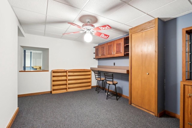 office with baseboards, carpet flooring, built in study area, a paneled ceiling, and a ceiling fan