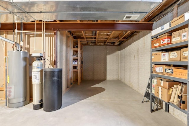 unfinished basement with visible vents, water heater, and brick wall