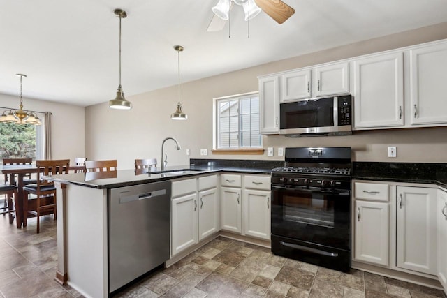 kitchen featuring a peninsula, a sink, hanging light fixtures, stainless steel appliances, and white cabinetry