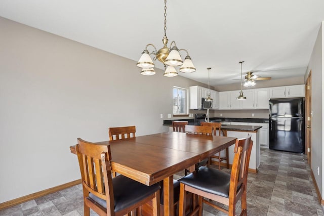 dining space featuring ceiling fan with notable chandelier, stone finish flooring, and baseboards