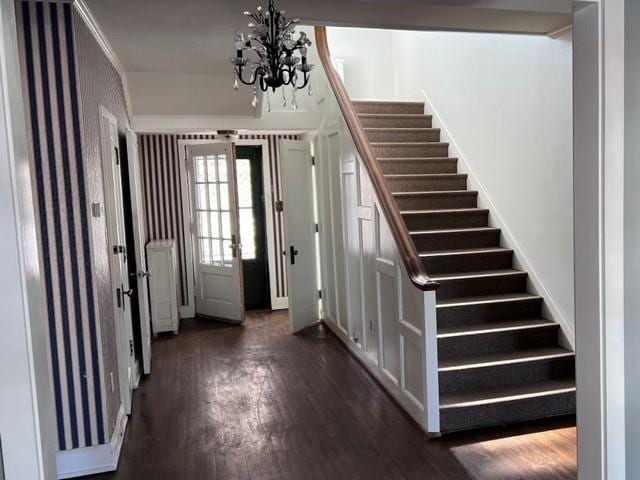 entrance foyer featuring stairs, an inviting chandelier, and dark wood-style flooring