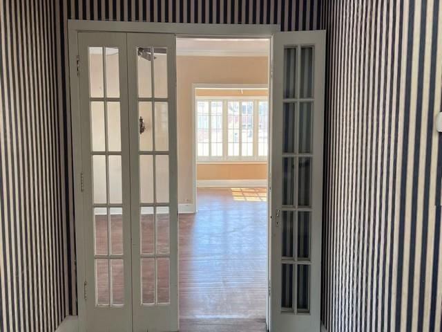 doorway to outside featuring french doors, baseboards, wood finished floors, and crown molding