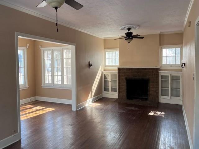 unfurnished living room with ceiling fan, a brick fireplace, wood finished floors, and crown molding