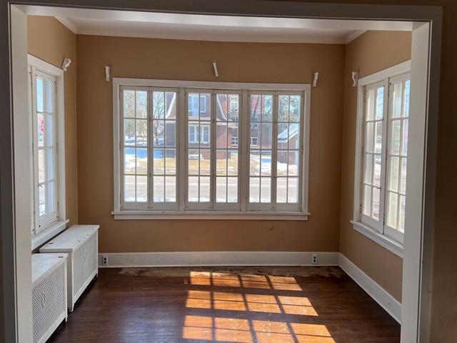 unfurnished dining area featuring crown molding, baseboards, and dark wood-style flooring