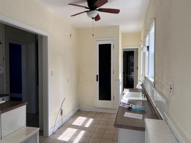 interior space with tile patterned flooring, a ceiling fan, baseboards, and a sink