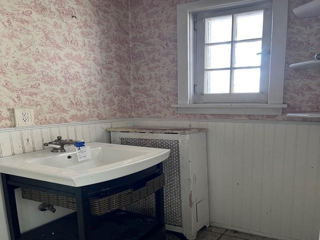 bathroom with a wainscoted wall, vanity, and wallpapered walls