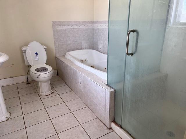 full bathroom featuring tile patterned floors, a shower stall, toilet, and a whirlpool tub