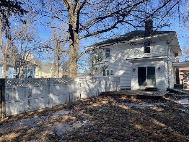 back of property featuring fence and a chimney