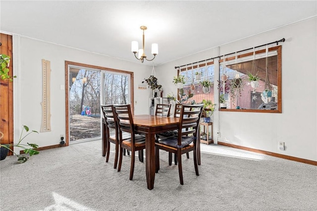 carpeted dining room featuring baseboards and a chandelier