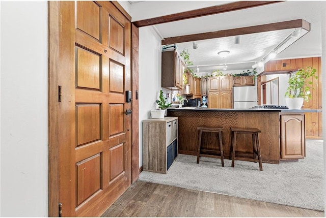 kitchen with a peninsula, a breakfast bar area, brown cabinetry, and freestanding refrigerator