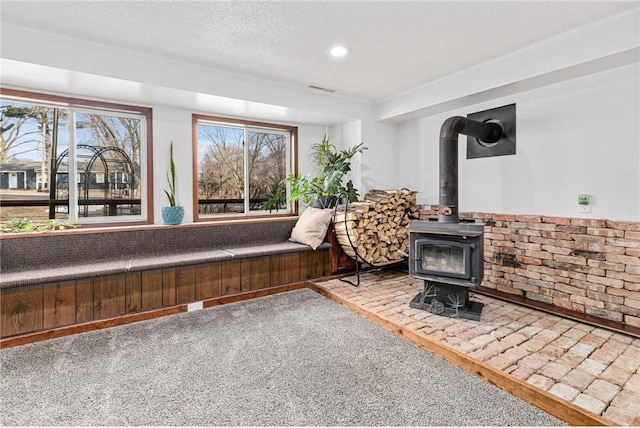 unfurnished room with plenty of natural light, recessed lighting, a textured ceiling, and a wood stove