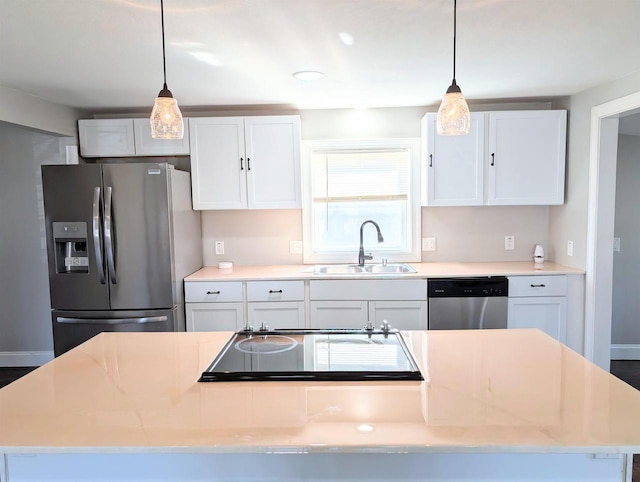 kitchen with hanging light fixtures, appliances with stainless steel finishes, light countertops, and a sink