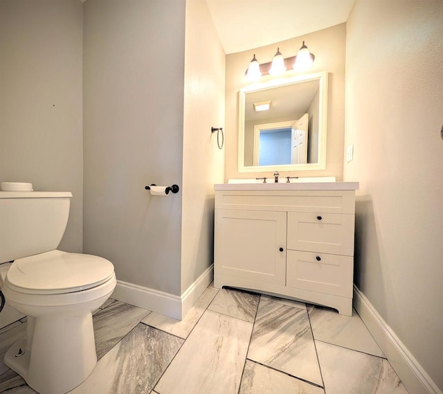 bathroom featuring marble finish floor, toilet, vanity, and baseboards