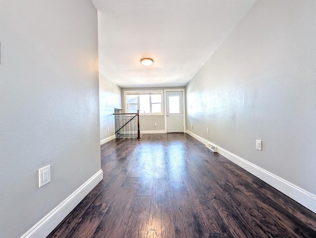 unfurnished room featuring visible vents, baseboards, and dark wood-style floors