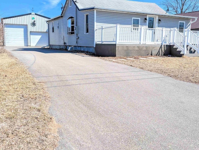 view of front facade with a detached garage, an outdoor structure, and roof with shingles