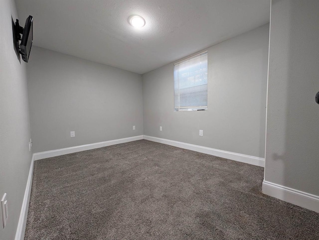 unfurnished room featuring dark colored carpet, baseboards, and a textured ceiling