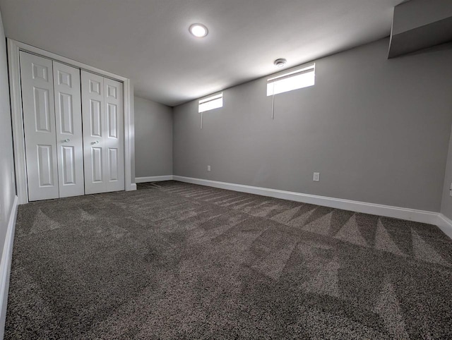 below grade area featuring baseboards and dark colored carpet