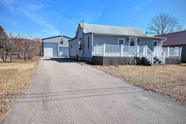 view of front of property featuring a garage, an outbuilding, a wooden deck, and driveway