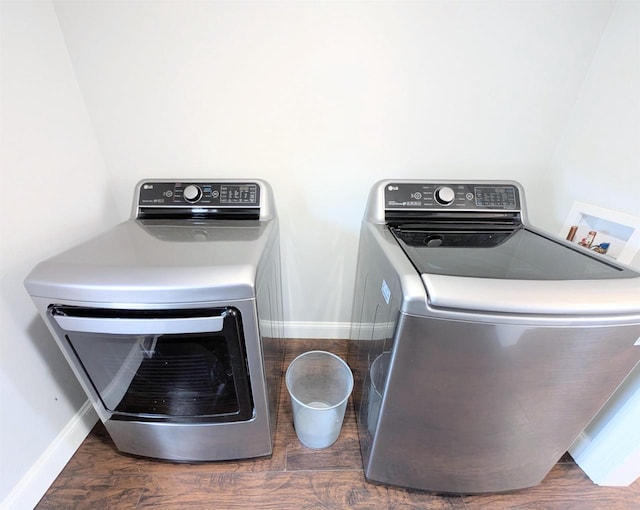 laundry room with baseboards, wood finished floors, washing machine and dryer, and laundry area