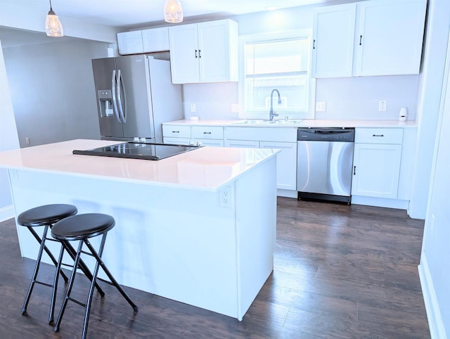 kitchen with a sink, a kitchen island, dark wood finished floors, white cabinetry, and stainless steel appliances