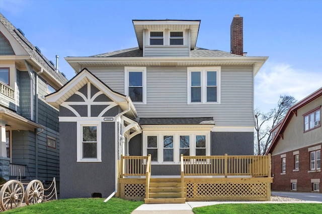 view of front of house featuring a chimney, stucco siding, a shingled roof, and a front yard