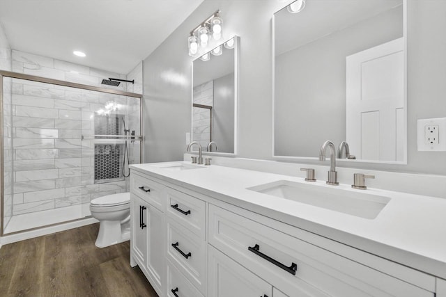 full bathroom with a sink, toilet, a stall shower, and wood finished floors